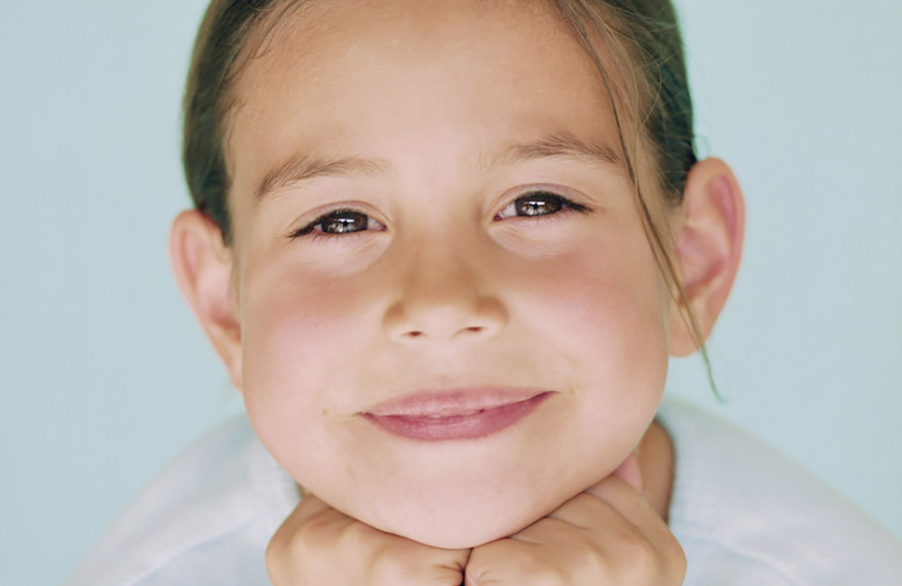 A cute little girl happily smiles at us