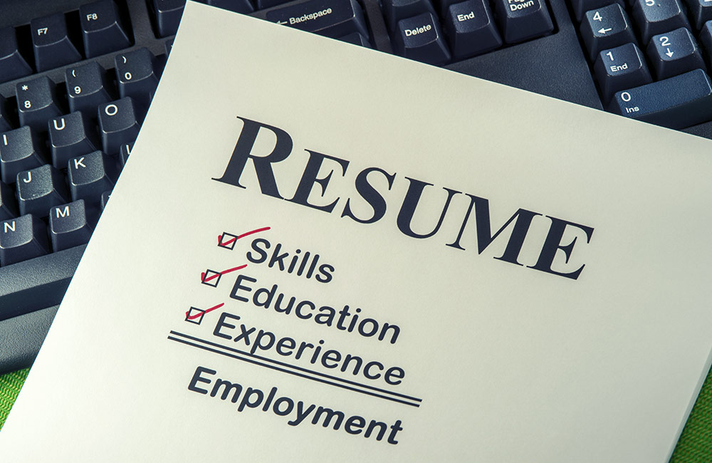 A printed resume sits on a computer keyboard