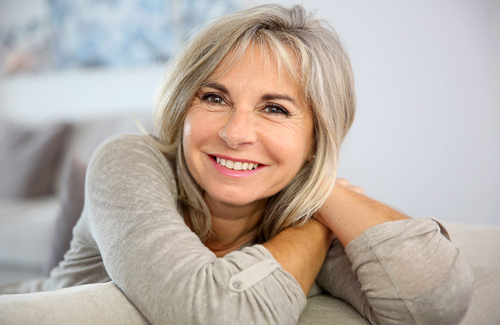 An attractive older lady sits and smiles