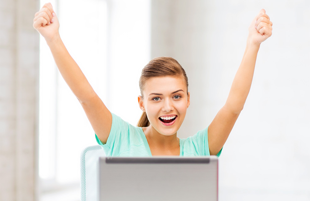 A pretty young girl celebrates with a smile and rasied arms